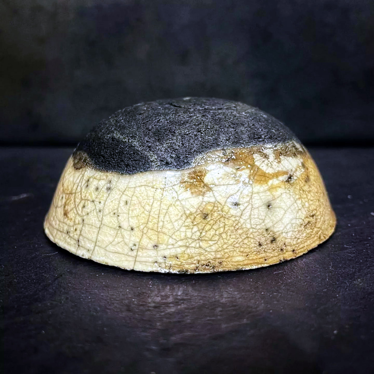 Low ceramic bowl with a pale crackled exterior and a dark smoke-blackened upper surface.